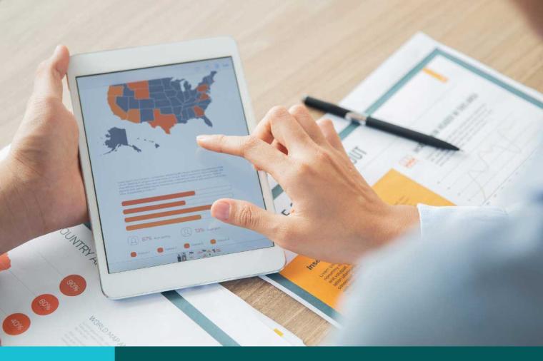 Hand of unrecognizable businessman holding digital tablet with USA map and chart. Hand of his female colleague pointing at map and touching screen. Documents lying nearby on table