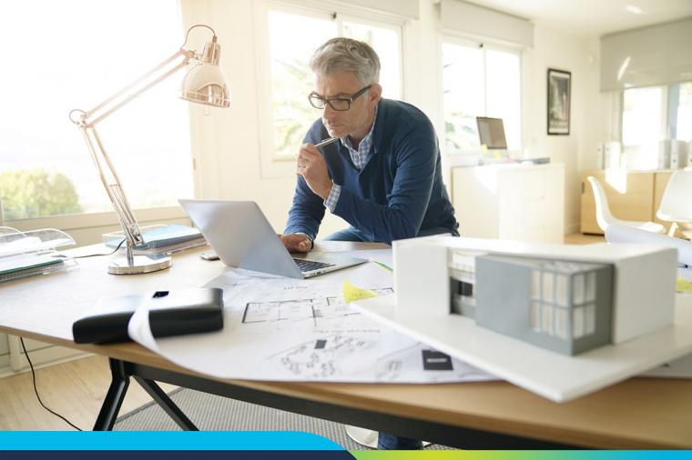 man standing at desk with laptop