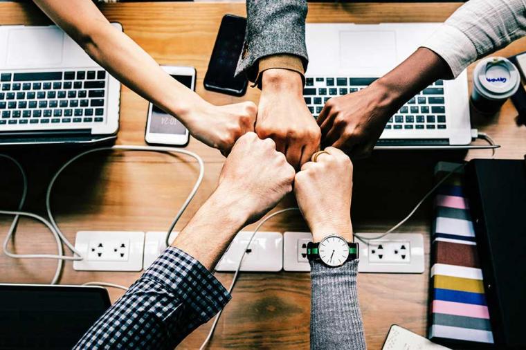 People fist-bumping over a conference room table