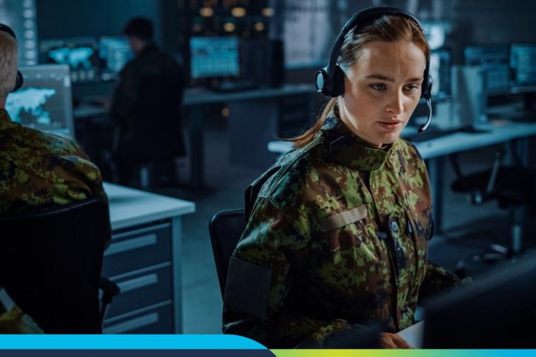 Female in uniform wearing a headset looking intently at a computer