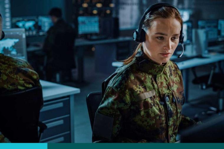 Female in uniform wearing a headset looking intently at a computer