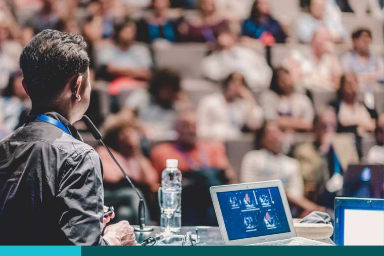 Looking out past a speaker in front of a conference audience