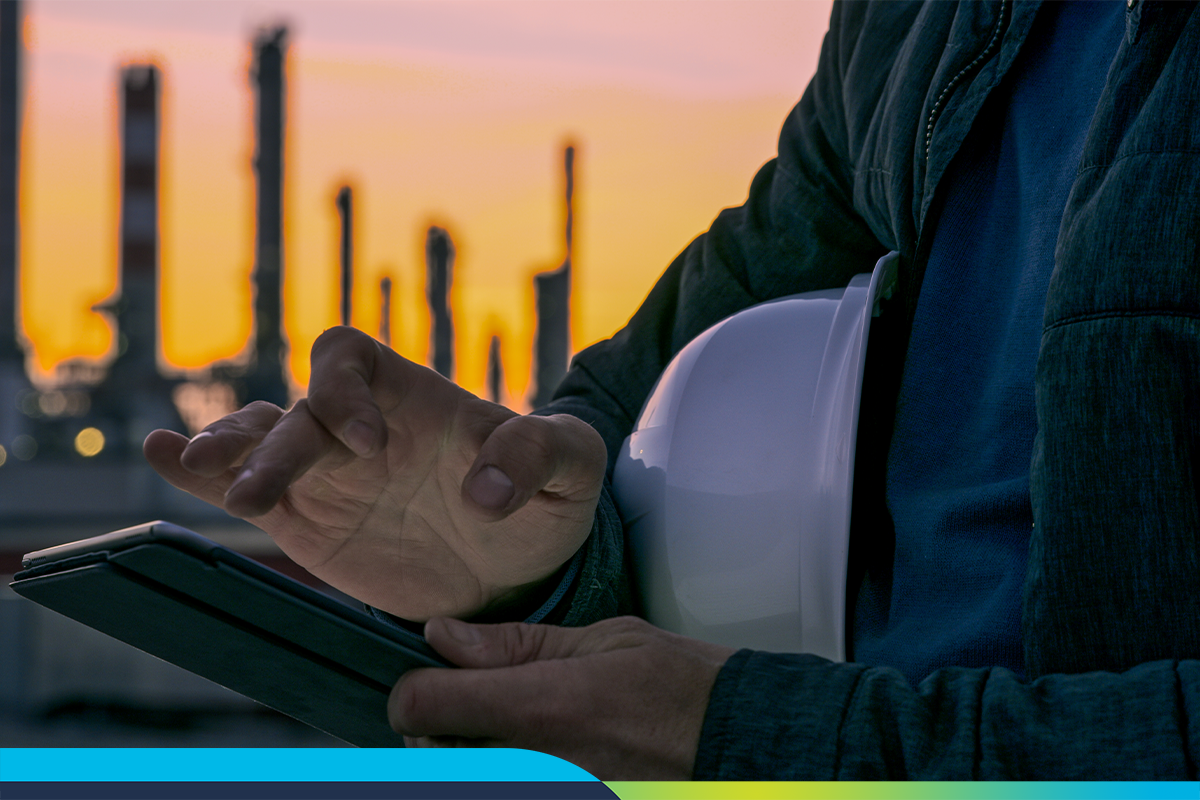 Man holding hard hat in front of oil refinery