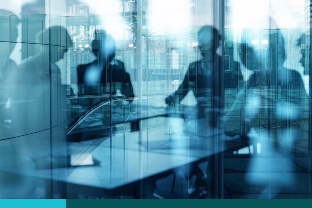 Blurred view through glass wall of 5 people around a conference room table