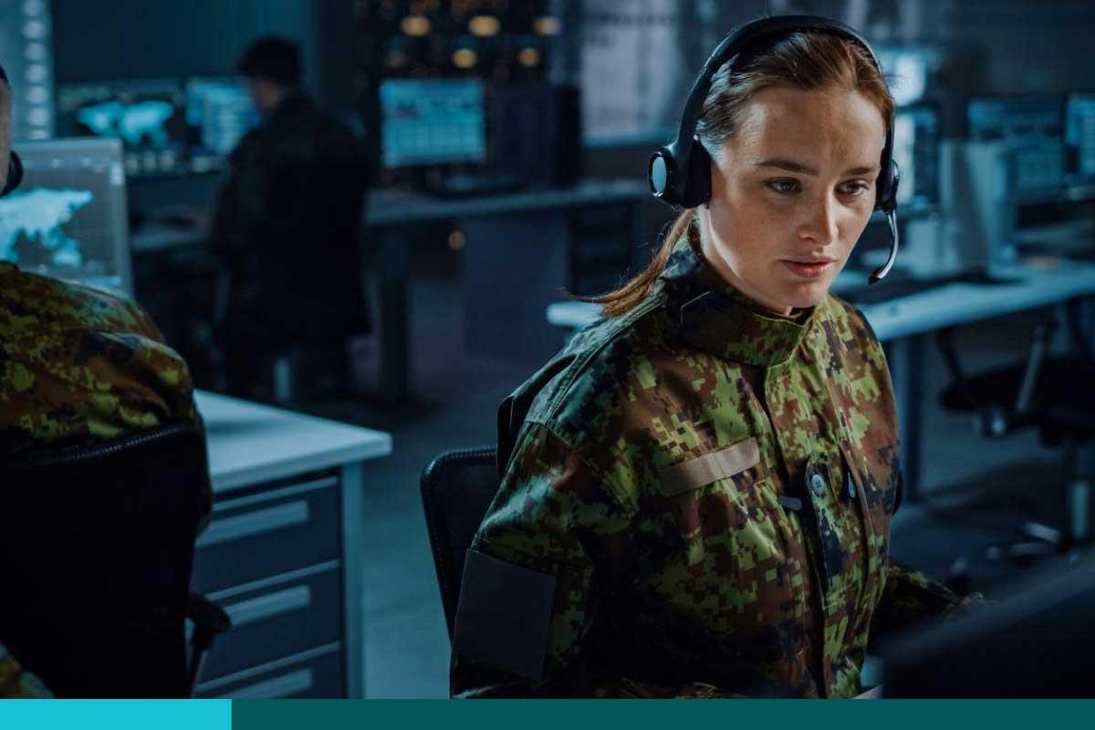 Female in uniform wearing a headset looking intently at a computer