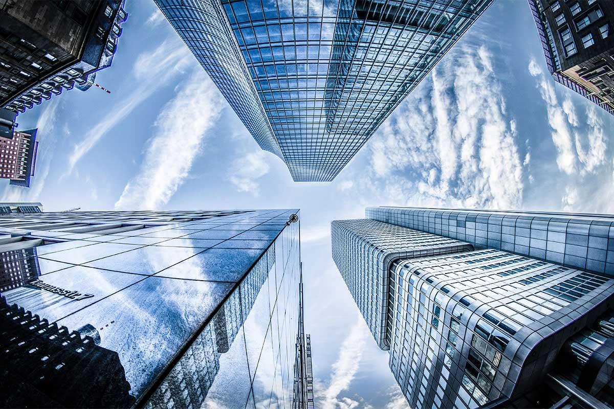 Ground view looking up between several glass buildings